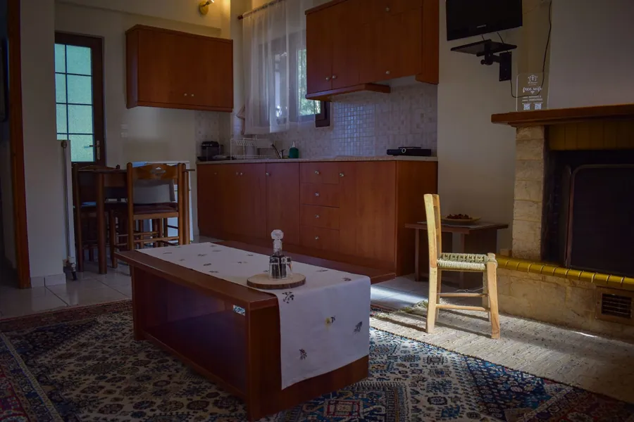 Σαλόνι με τζάκι, ξύλινο τραπεζάκι και κουζίνα στο βάθος
